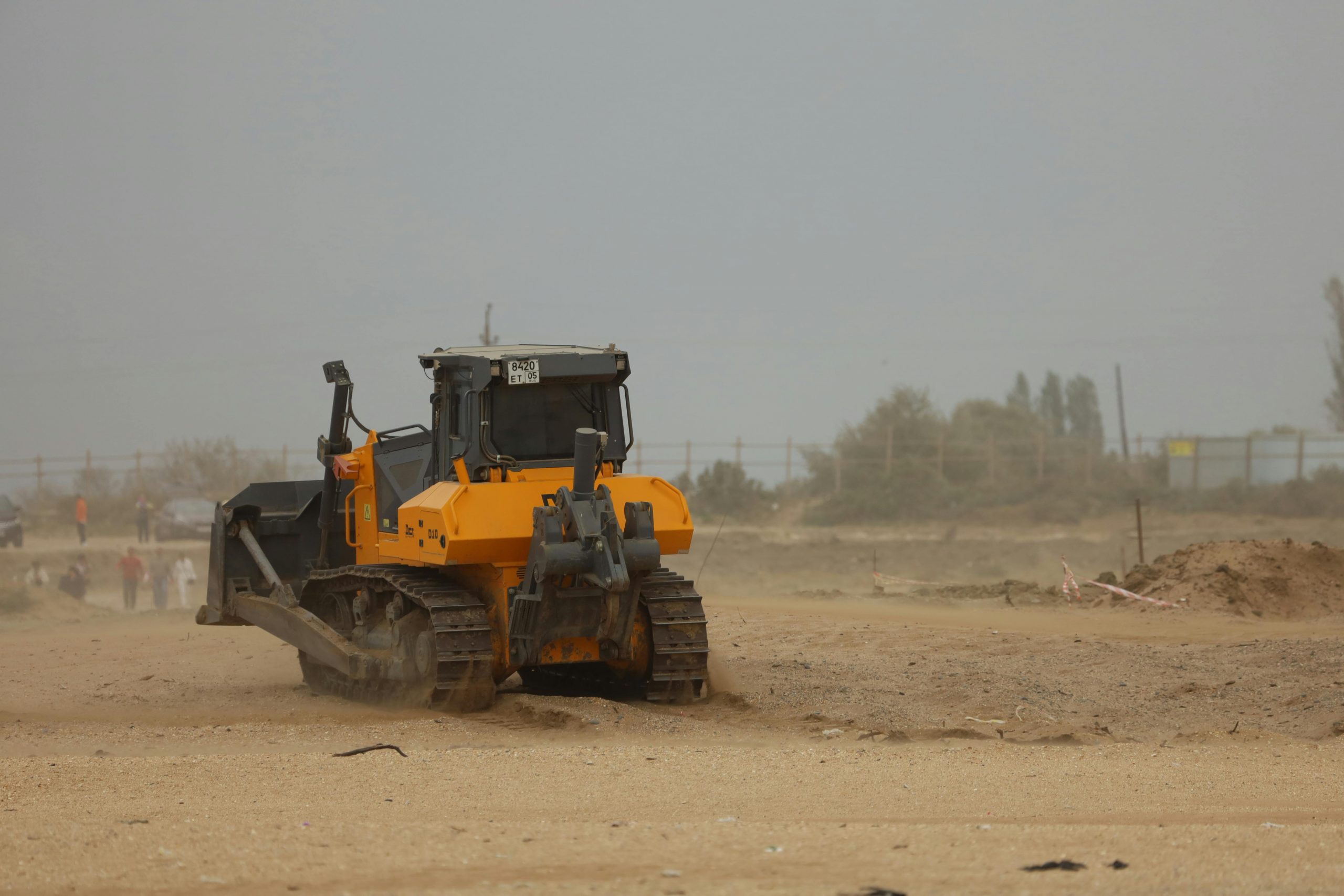 A large bulldozer with continuous tracks working on a dusty construction site.
